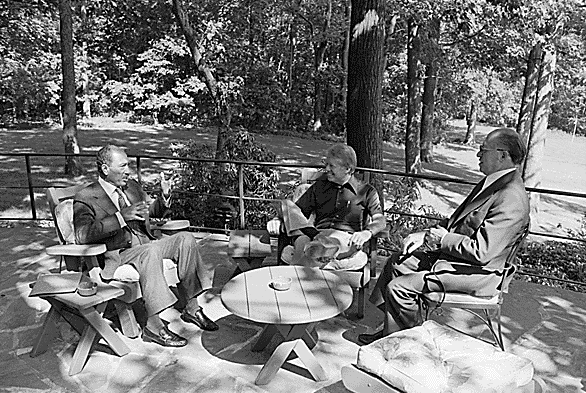 Presidents Sadat, Carter and Prime Minister Begin meet on the Aspen Cabin patio at Camp David in this White House staff photo. Credit Bill Fitzpatrick