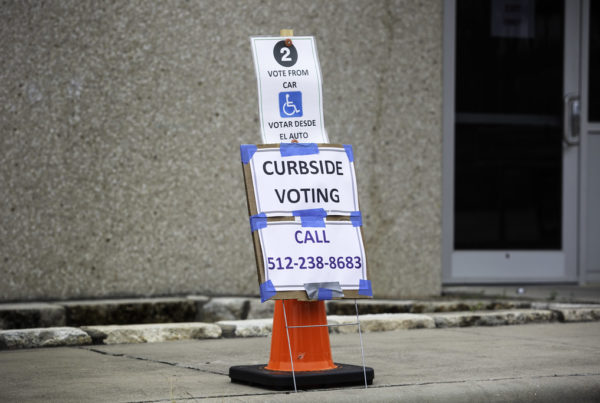 a sign that says "curbside voting" and lists a phone number to call.