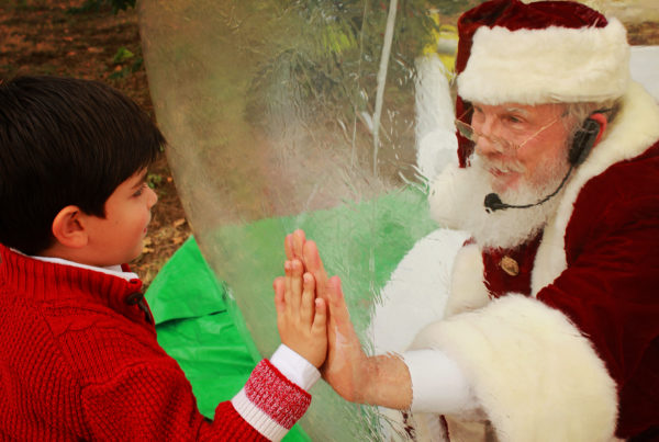 a man dressed as santa inside a snow globe with a child on the other side