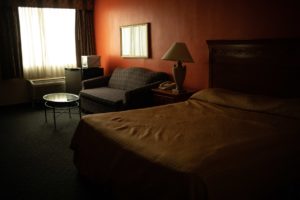 A hotel room with couch, bed, lamp and small table