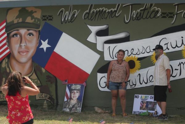 A couple posing for a photo in front of a mural for the murdered soldier Vanessa Guillen