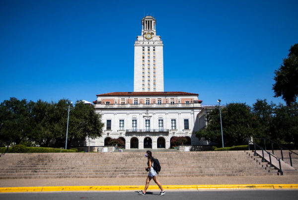 A student walking in front of steps leading to the university of texas at austin tower