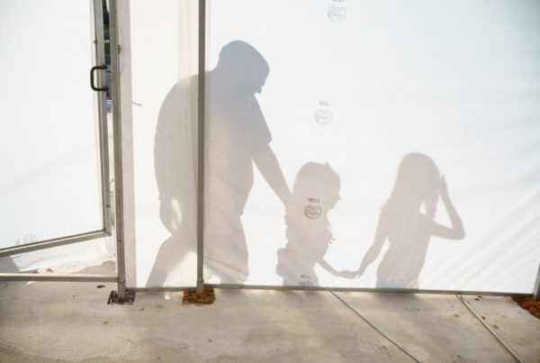 shadows of a man and his daughters on a white wall