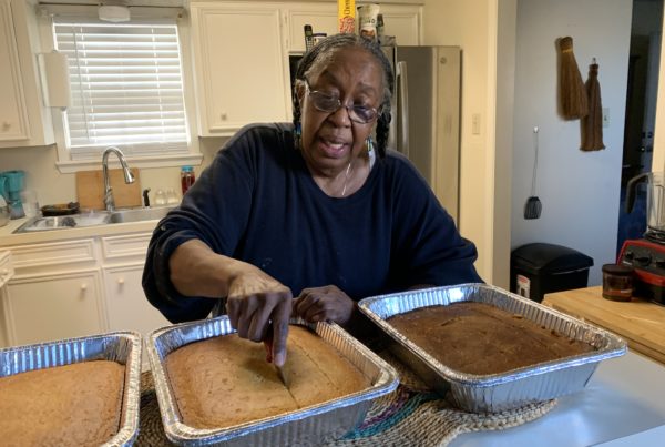 a woman slicing a large tray of cornbread