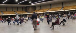 people waiting in spaced out chairs to get vaccinated in Lubbock's civic center