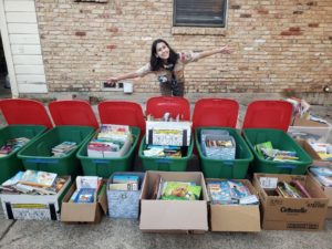 a female eagle scout in front of several tubs of books