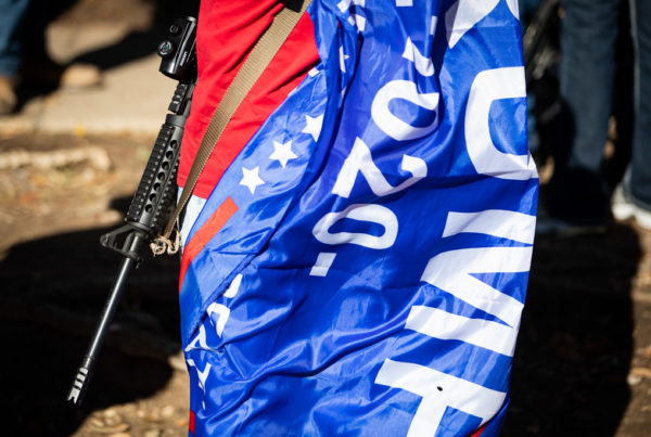 a trump flag and a large gun strapped around a person's body