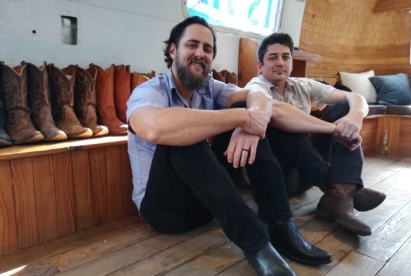 two men sitting on the ground in front of cowboy boots