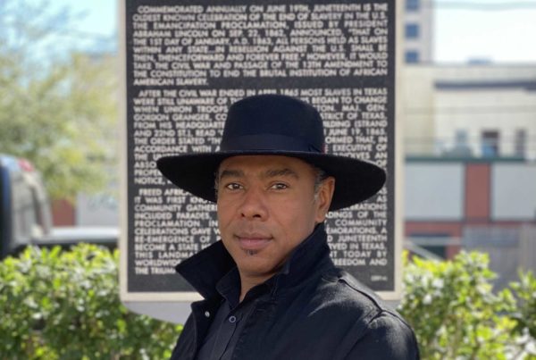 a man wearing a hat standing in front of a memorial plaque