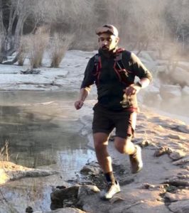 a man running on rocks by a creek