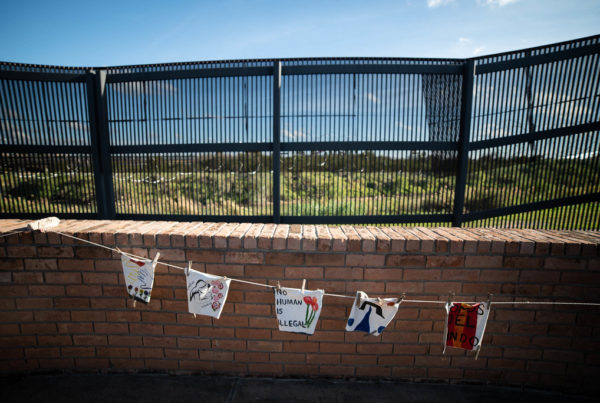 hand-painted flags hang in front of a border fence