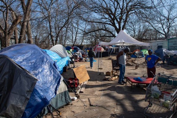 people standing in front of tents at a homeless camp