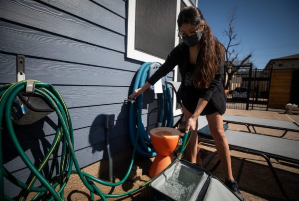 a woman filling up a cooler with water from a hose