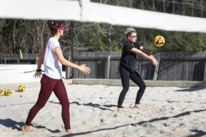 two women playing volleyball in a sand court