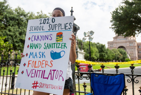 a teacher with a protest sign in front of texas capitol