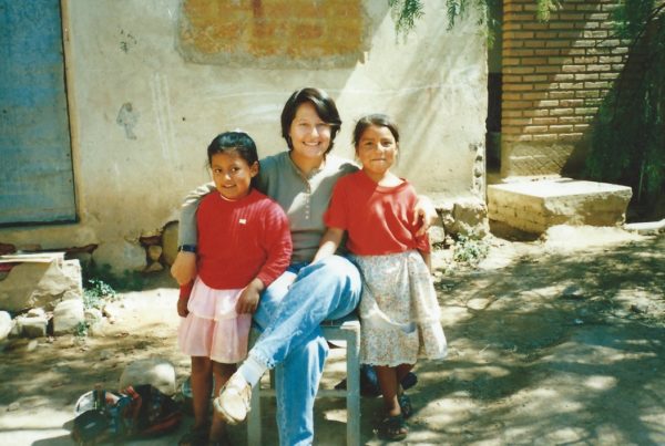 a woman sitting with two young girls on either side wearing read shirts