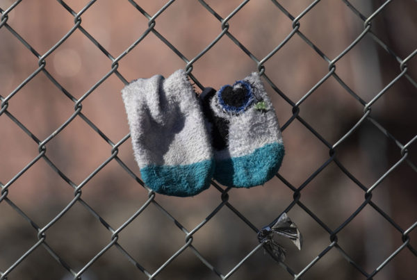 young child's socks hanging on a chainlink fence