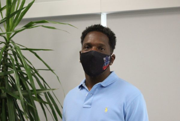 a man standing with a face mask and blue polo shirt