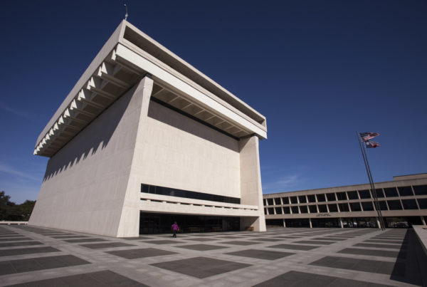 a view of the LBJ Library from one corner, looking up, with another building in the background.