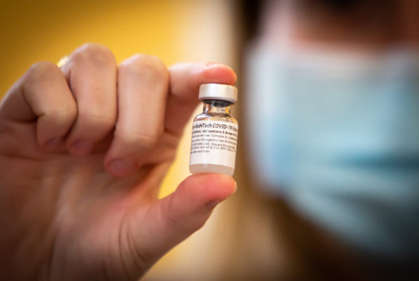 a person holding a vial of the covid 19 pfizer vaccine