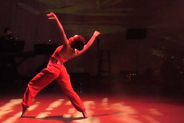 a woman dancing on a stage with red lighting