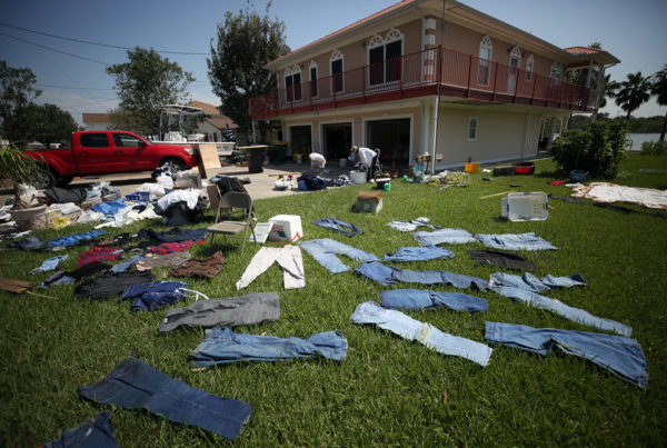 jeans drying out on a lawn in front of a flooded home after hurricane harvey