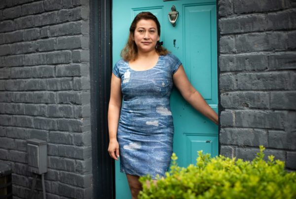 a woman standing in a blue dress in front of a teal door