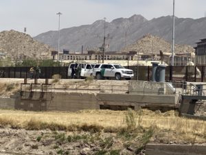 mountains at border in el paso with border patrol trucks and people in front of them