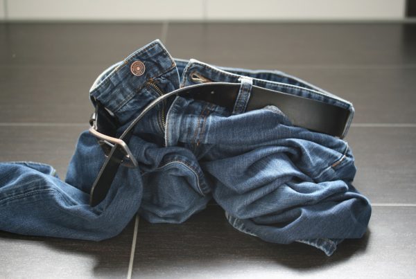 a pair of jeans lay discarded on a tile floor