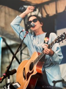 Nanci Griffith on stage, with guitar, wearing sunglasses