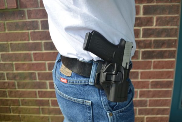 A person carries a gun holstered at the hip.