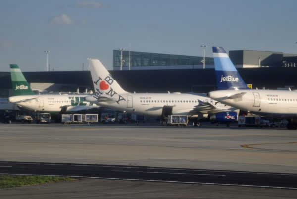 three JetBlue planes, painted with different paterns, lined up at an airport
