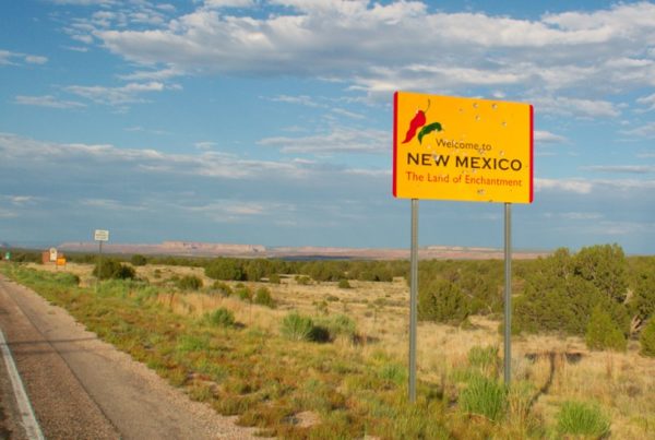 a desolate landscape with a "welcome to New Mexico" sign in the foreground