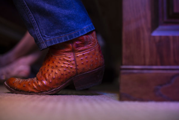 a close-up photo of a person wearing cowboy boots in a church pew