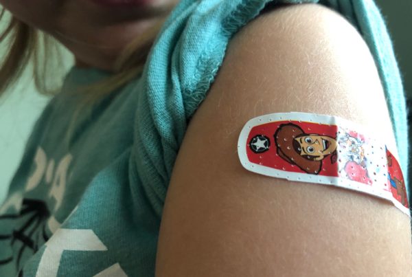 a child's arm with a Bandaid near the shoulder