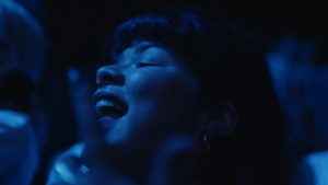 a blue light shines on a smiling Doris Muñoz in the film 