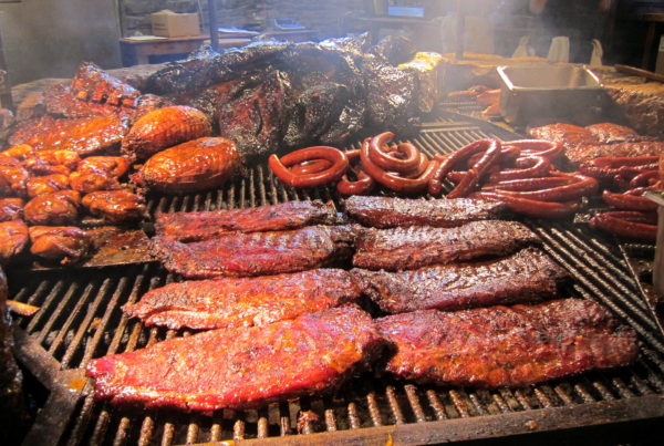 A rack filled with cooking meat in a large BBQ pit