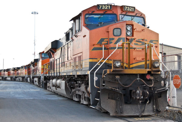 an orange train engine with BNSF painted on the front and several train cars behind it
