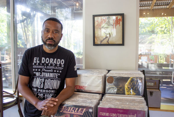 a man stands next to a collection on vinyl records