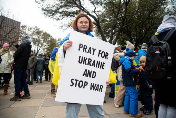 a protester holds a sign that says "Pray for Ukraine"