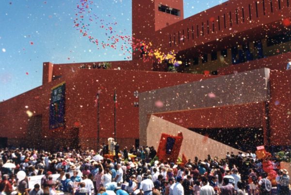the brick-red san antonio library with sharp angles in the large building, and many people standing outside of it on its opening day
