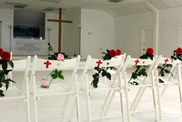a white church room with white chairs and roses on each chair