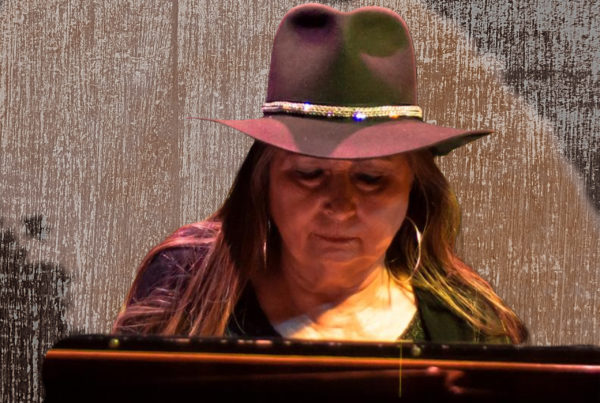 a woman with long brown hair, a brown cowboy had sitting at a piano