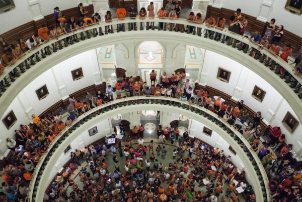 people in orange shirts fill balconies in the rotunda of the Texas Capitol
