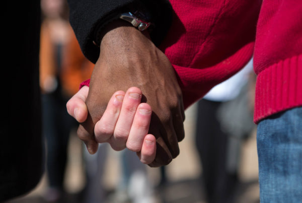 a closeup of two unidentifiable people with different skin tones holding hands
