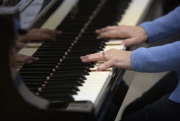 two hands are seen playing a piano