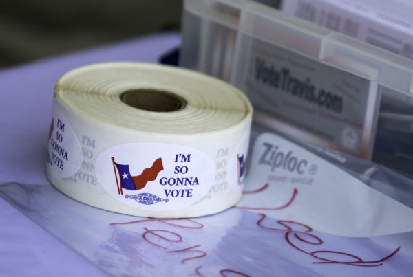 A roll of stickers that say "I'm so gonna vote" next to the Texas flag