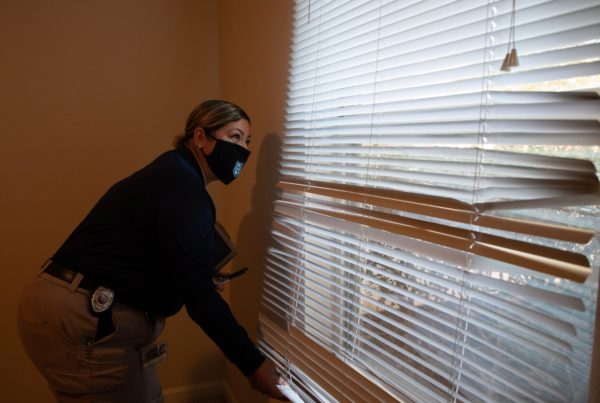 A code inspector looks at damaged window blinds