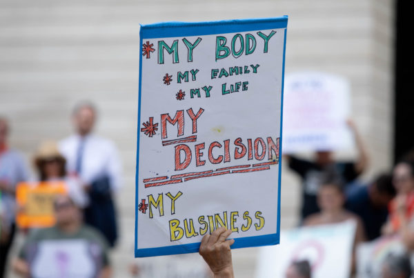 A person at a protest holds a sign reading, "My body, My decisions, My business."