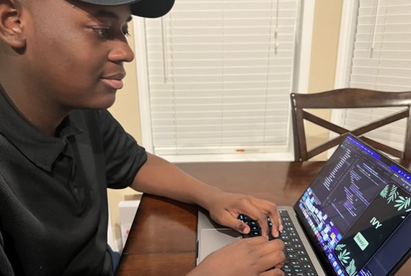 A profile view of Jones Mays, using his laptop to create code.